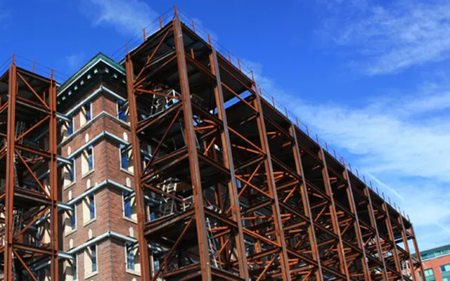 Steel-framed building under construction beneath a tower crane