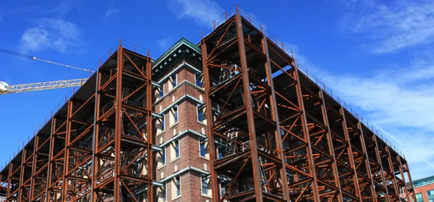Steel-framed building under construction beneath a tower crane